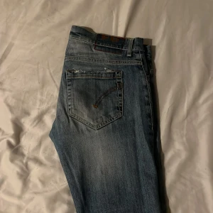 Dondup Jeans 30W 31L passar 32L - Snygga blå jeans från Dondup med slit och hål på ena benet. Modellen är slim fit/skinny med klassisk femficksdesign och ljusa tvättade partier.