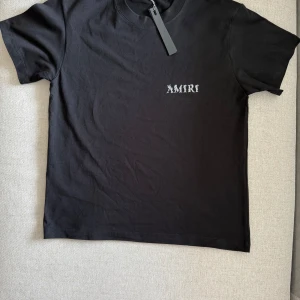 Svart AMIRI t-shirt med tryck - Svart t-shirt från AMIRI i mjuk bomull med klassisk passform. Stor AMIRI-logga i vitt på ryggen och mindre tryck framtill. Storlek S 