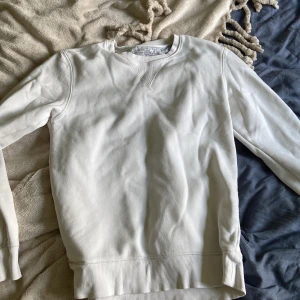 Vit sweatshirt från Crocker - En stilren vit sweatshirt från Crocker med klassisk rund halsringning och ribbade muddar. Tröjan är i mjuk bomull och har en relaxed passform som är perfekt för chill dagar. Enkel design utan tryck eller mönster, passar till allt. Passar för både tjej och kille! 