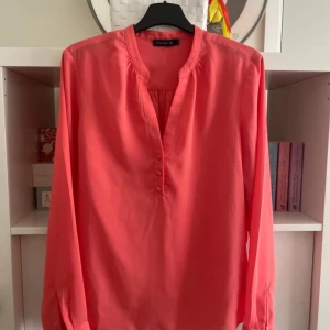 Korall blus  - En väldigt fin blus i en slags korall rosa ton med luftigt och sommarperfekt material. Använts få gånger och är i väldigt bra skick. 