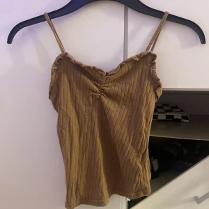 Ribbad brun linnetopp från SHEIN - Supersöt brun ribbad linnetopp från SHEIN med smala axelband och lätt rynk vid bysten. Toppen har en croppad passform och är perfekt för varma dagar. Materialet är mjukt och stretchigt, vilket gör den riktigt bekväm att bära.