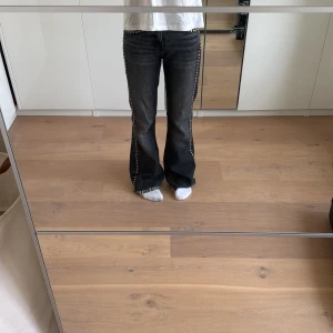 Svarta bootcut jeans med nitar - Jag säljer dessa super coola svarta jeans med silvriga detaljer på sidan. Jag säljer för dom börjar bli för små. Jeansen är inte upp gångna där nere dom ser ut så från början💗 priset kan diskuterasssss