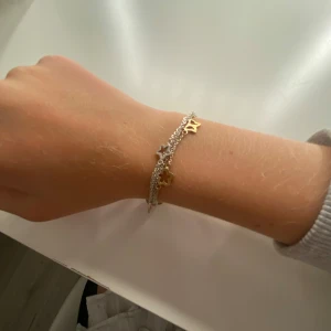 Fint armband med flera kjedjor🫶🏻 - Fint armband i silverfärgad metall med flera kedjor och berlocker i form av hjärtan, stjärnor och blommor i både guld och silver. Stängs med en stor guldfärgad hjärtformad låsdel. Perfekt för dig som gillar detaljer och mixade färger🫶🏻