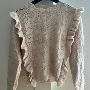 Beige stickad tröja med volang - Supersöt beige stickad tröja med volangdetaljer längs axlarna och ärmarna. Köpt på missäy från by Clara 