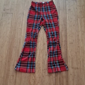 Röda rutiga bootcut-byxor Shein Teen - Snygga röda bootcut-byxor från Shein Teen med klassiskt rutigt mönster i svart, vitt . Byxorna har hög midja och är tillverkade i ett mjukt syntetmaterial som sitter skönt. Perfekta för dig som vill sticka ut med en cool retrostil.
