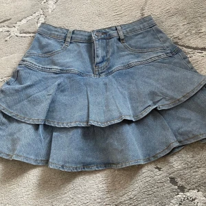 Jeanskjol med volanger - Supersöt blå jeanskjol med två lager volanger och klassiska fickor fram. Den har endast använts 1 gång och har även inbyggda short!
