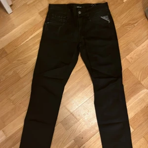 Svarta Replay slim jeans - Snygga svarta jeans från Replay med klassisk femficksdesign och diskret logga på fickan. Jeansen har en slim passform och raka ben, perfekta till sneakers eller boots. Tillverkade i mjukt och stretchigt jeansmaterial för extra komfort.