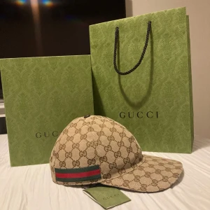 Beige keps från Gucci monogram.  - Snygg beige keps från Gucci med klassiskt GG-monogram, kommer med låda. Perfekt accessoar för dig som vill sticka ut med lyxig streetstyle. Justerbar baktill för bästa passform.