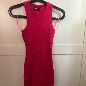 Rosa ribbad kortklänning  - Snygg rosa ribbad kortklänning. Ärmlös modell med rund halsringning och tight passform. Perfekt för dig som vill ha en enkel men ändå trendig look. Klänningen är i stretchigt material som sitter skönt på kroppen.