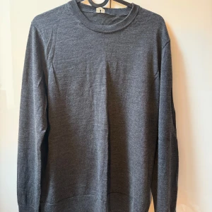 Mörkgrå stickad tröja - En stilren mörkgrå stickad tröja från ARKET med rund halsringning och långa ärmar. 