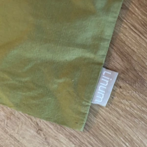 Linum grönt kuddfodral + 2 mörkblå kuddfodral - Tre kuddfodral. Ett olivgrönt från Linum, och två mörkblå. Båda är fyrkantiga och tillverkade i ett mjukt bomullstyg, perfekta att bära med sig till stan eller skolan. Enkla och minimalistiska med diskret Linum-tag på sidan.
