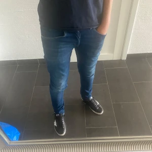 Dondup George - Säljer ett par blå skinny jeans från George. Jeansen har klassisk femficksdesign, kontrastsömmar och en snygg mörkblå tvätt med lätt slitning. De är stretchiga och sitter tajt längs benen för en modern look. Perfekta till sneakers och t-shirt.