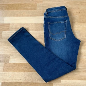 Slim fit jeans från Jack & Jones - Snygga blå slim fit jeans från Jack & Jones, modell Glenn. Klassisk femficksdesign, normalhög midja och smal passform. Jeansen är gjorda i stretchig bomullsdenim för extra komfort och har snygga kontrastsömmar.