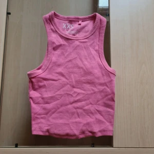 Rosa ribbad linnetopp - Säljer en söt rosa ribbad linnetopp från FSBN Sister (new yorker) i storlek XXS. Toppen är ärmlös med klassisk rund halsringning och croppad passform. Perfekt för varma dagar eller att styla lager på lager. Superenkel att matcha med jeans eller kjol! Går att köpa 3-pack (kolla mina annonser)