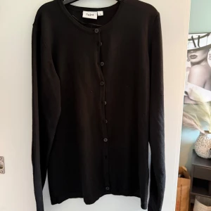 Svart kofta från Saint Tropez - Svart, klassisk kofta från Saint Tropez i storlek S. Koftan har rund hals, långa ärmar och knäppning med svarta knappar framtill. Materialet är mjukt och stickat, perfekt för lager-på-lager och chill stil. Enkel design som funkar till många outfits. Används inte längre därav att jag säljer den💕