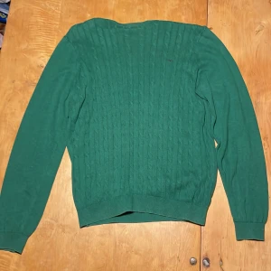 Grön kabelstickad tröja Hampton Republic - Snygg grön kabelstickad tröja från Hampton Republic. Tröjan har rund halsringning, ribbade muddar och lång ärm. Perfekt för dig som gillar klassisk stil med en modern twist. Materialet är mjukt och skönt, passar till många olika outfits.