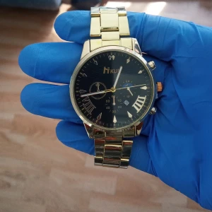 Guldig Miku klocka med svart urtavla - Stilren klocka från Miku med guldig länk och svart urtavla. Klockan har romerska siffror, flera dekorativa subdials och datumvisning. Metallarmbandet ger en lyxig känsla och passar perfekt till dig som gillar klassisk design med modern touch.