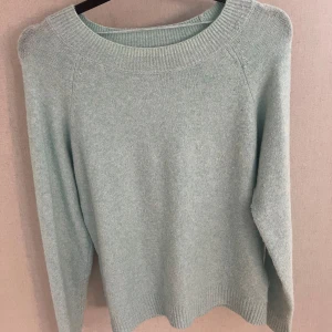 Ljusblå stickad tröja från Vero Moda - Mysig ljusblå stickad tröja från Vero Moda med rund hals och ribbade muddar. Perfekt för att hålla sig varm under kyliga dagar. Enkel och stilren design som är lätt att matcha med dina favoritjeans eller kjol.