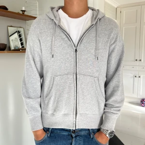 Ljusgrå hoodie med dragkedja - Säljer en ljusgrå hoodie från Uni Qlo. Knappt använd då jag köpte en storlek för litet och har därmed inte kommit till större användning. 