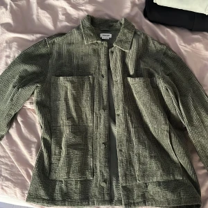 Grön manchester overshirt från Weekday - Säljer en grön overshirt i manchester från Weekday, modell Roland Cord. Jackan har två stora bröstfickor, knäppning framtill och klassisk krage. .