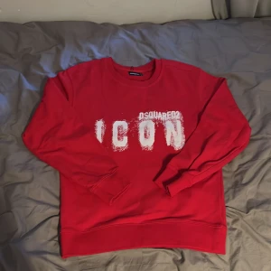 Röd Dsquared2 ICON sweatshirt S - Riktigt snygg röd sweatshirt från Dsquared2 med stort vitt 'ICON'-tryck framtill. Tröjan har rund hals, ribbade muddar och är i mjuk bomull. Perfekt statement-plagg för dig som vill sticka ut och visa stil.