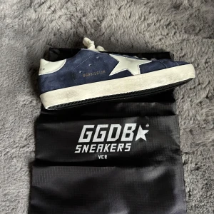 Mörkblå golden goose - Golden Goose Superstar sneakers i mörkblå mocka med vit stjärndetalj på sidan och vit häl. Klassisk låg modell med snörning och platt sula. Snygg kontrast mellan blå mocka och vita detaljer, perfekt för dig som gillar streetstyle. Helt nya allt og! 41-42