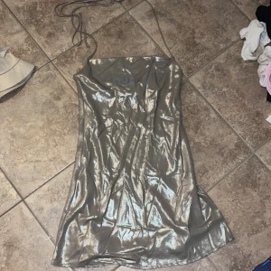 Glittrig silverklänning Gina Tricot - Supersnygg glittrig silverfärgad kortklänning från Gina Tricot med tunna axelband. Klänningen har en slinkig passform och skimrande yta som verkligen sticker ut. Perfekt för dig som vill glänsa och synas! Strl S.