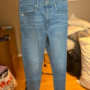 Levi's Mile High Super Skinny jeans i ljusblå denim - Säljer ett par Levi's Mile High Super Skinny jeans i ljusblå denim. Jeansen har hög midja, klassiska fem fickor och smal passform hela vägen ner. Perfekta för dig som gillar en tight och modern look.