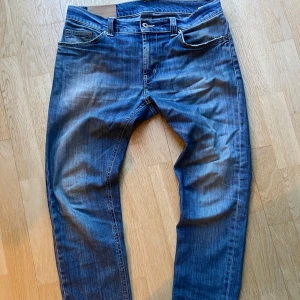 Blå jeansbyxor från dondup - Säljer ett par klassiska blå jeansbyxor från dondup med fem fickor. De är en skinny fit, perfekt för en avslappnad stil. Diskreta detaljer och logga på bakfickan.