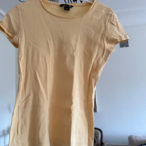 Gul t-shirt från H&M - En enkel gul t-shirt från H&M med rund halsringning och korta ärmar. Tillverkad i mjuk bomull, perfekt för varma dagar. Klassisk passform som funkar till det mesta.