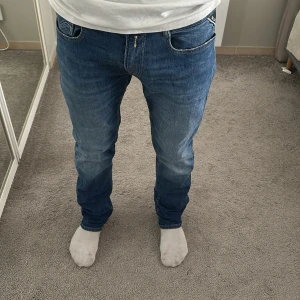 Replay Rocco - Säljer ett par klassiska blå jeans från Replay rocco med raka ben och normal passform. Jeansen har fem fickor, snygga slitningar och en cool tvätt. Perfekta för dig som gillar en tidlös stil och vill ha ett par jeans som funkar till allt.
