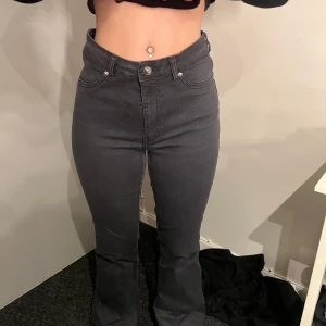 Grå bootcut jeans - Säljer ett par gråa bootcut jeans med hög midja. Jeansen har klassisk femficksdesign, dragkedja och knapp framtill. Snygg passform som sitter tight upptill och släpper ut vid bensluten.