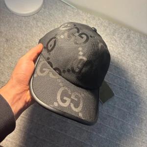 Svart gucci keps - Skicka dm för video eller prisförslag! Snygg svart keps från Gucci med det klassiska GG-mönstret i grått. Kepsen har böjd skärm, justerbart spänne bak och är tillverkad i ett slitstarkt material. Perfekt för att lyfta din outfit med en lyxig touch. Storlek ”M”