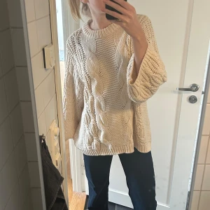 Beige stickad kabeltröja - Säljer en chunky beige stickad tröja från VeroModa med grovt kabelstickat mönster och breda ärmar. Perfekt för lager-på-lager och riktigt mysig till sommarkvällar. Rund halsringning och avslappnad passform.