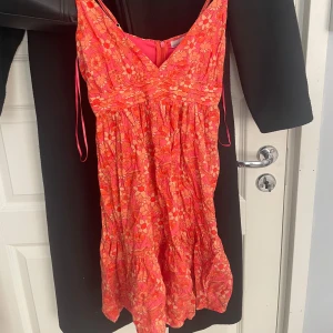 Blommig kortklänning  - Supersöt kortklänning med blommigt mönster i rosa och orange toner. Den är ifrån Pull&Bear och i storlek S, säljer då den tyvärr inte kommer till användning!