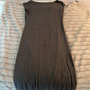 Mörkgrå ärmlös klänning från H&M - En enkel och stilren mörkgrå klänning från H&M. Modellen är ärmlös med rund halsringning och har en rak passform som smalnar av nertill. Mjuk och stretchig bomullskvalitet som gör den bekväm att bära hela dagen. Den har använts en gång.