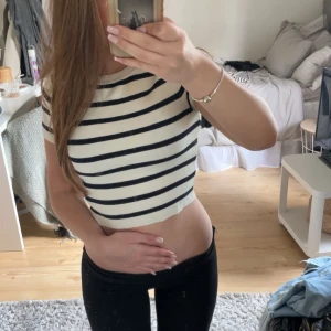 Vit och svart randig croppad topp från Zara - Säljer en croppad topp från Zara i vitt med svarta horisontella ränder. Toppen har korta ärmar och rund halsringning. Perfekt till jeans eller kjol för en trendig look.