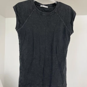 Svart ärmlös topp från Zara - En enkel svart ärmlös topp från Zara med rund halsringning. Perfekt att styla till jeans eller kjol för en clean look. Mjuk bomullskänsla och rak passform.