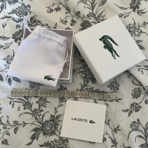 Silverfärgat armband från Lacoste - Stilrent armband från Lacoste. Kommer i original ask och tygpåse med Lacoste-logga. Perfekt accessoar för en clean och modern look. den perfekta presenten att ge sin pojkvän eller bror. PRIS KAN DISKUTERAS VID SNABB AFFÄR