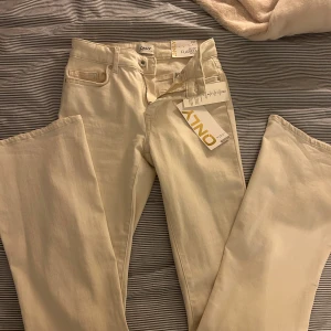 Beige flared byxor från ONLY - Säljer ett par snygga benvita flared byxor från ONLY. De har en midwaist passform och är perfekta för en trendig look. Byxorna har en klassisk dragkedja och knapp framtill. Aldrig använda🤍🤍