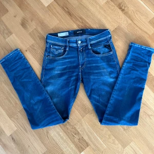 Blå Replay Anbass jeans  - Snygga blå jeans från Replay med klassisk femficksdesign och dragkedjegylf. Modellen är Anbass. De har en stilren look som är perfekt för en avslappnad stil.