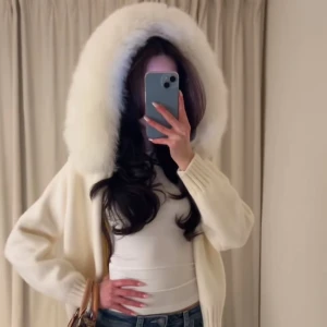 alessa vit jacka - Elegant vit kappa med stor huva kantad av fluffig päls. Perfekt för kyliga dagar när du vill hålla dig varm och stilren. Jackan har en avslappnad passform och långa ärmar.