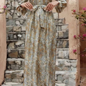 Mönstrad långklänning i siden med knytband - Elegant långklänning i siden med ett vackert mönster i beige och blå toner. Klänningen har långa ärmar och ett knytband i midjan för en smickrande passform. Perfekt för en stilfull look. Använd 1-2 gånger.