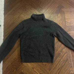 Mörkgrå stickad polotröja från Uniqlo - Säljer en stilren mörkgrå stickad polotröja från Uniqlo. Tröjan har en klassisk polokrage och långa ärmar, perfekt för kyligare dagar. Den är tillverkad i ett mjukt och bekvämt material som håller dig varm. Passar utmärkt till både jeans och chinos.