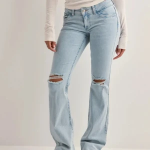 Nelly bootcut jeans  - Snygga ljusblå bootcut jeans med slitningar på knäna och coola broderade detaljer på bakfickorna. Perfekta för en avslappnad stil med en touch av edge. Högmidjade och i ett klassiskt jeansmaterial.