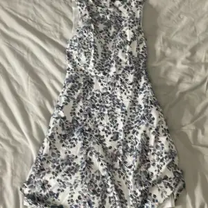 Säljer en vacker blommig klänning från Stockh LM i storlek 34. Klänningen har ett fint blommönster i blå och lila nyanser på en vit bakgrund. Den är ärmlös och har en dragkedja i ryggen. Perfekt för sommarens alla tillfällen!