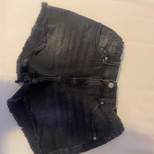 Svarta jeansshorts från Zara - Snygga svarta jeansshorts från Zara med fransiga kanter. Perfekta för en avslappnad stil. De har en klassisk femficksdesign och knappgylf.
