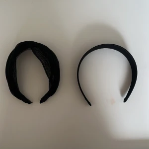 Svarta diadem i olika stilar - Två svarta diadem till salu. Det ena är bredare med en ribbad textur, perfekt för en elegant look. Det andra är smalare och enkelt, idealiskt för vardagsbruk. Båda är bekväma och lätta att bära.