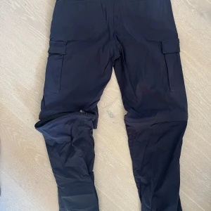 Friluftsbyxor från Tierra - Marinblå med avtagbara ben - Snygga blå friluftsbyxor / cargopants med praktiska fickor och avtagbara ben för en flexibel stil när du är ute i naturen. Perfekta för en aktiv livsstil. Strl junior 164. Använda 1 gång. Rök och djurfritt hem.