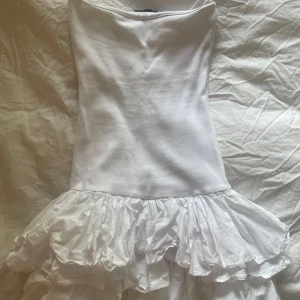 Axelbandslös klänning zara - Säljer en söt vit axelbandslös klänning från Zara. Den har en volangdetalj vid fållen som ger en lekfull touch. Perfekt för sommarens alla tillfällen!❣️❣️ endast använd en gång, säljer pga att den har blivit för liten